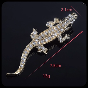 Detailed view of gold crocodile brooch with dimensions 7.5cm by 2.1cm and clear rhinestones