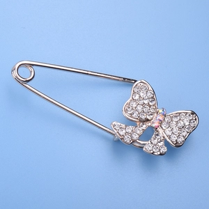 Elegant bow-shaped brooch with white rhinestones on light blue background