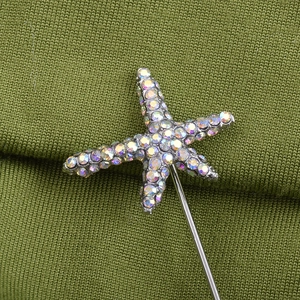 Macro shot of colorful rhinestone starfish pin on green knit fabric sweater texture