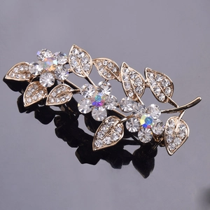 Élégante broche fleur dorée avec cristaux scintillants et détails de feuilles sur fond sombre