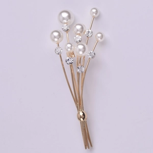 Élégante broche bouquet de fleurs dorée avec perles blanches et cristaux sur fond gris