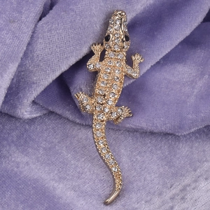 Elegant gold crocodile brooch paved with clear crystals on luxury purple velvet base