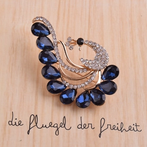 Elegante spilla a pavone in lega dorata con cristalli blu e strass bianchi lucidi