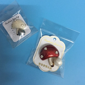Détail de broches en perles de champignons rouges et blanches sur fond bleu