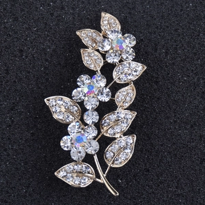 Détail macro d'une broche feuille dorée ornée de strass en cristal aux reflets changeants