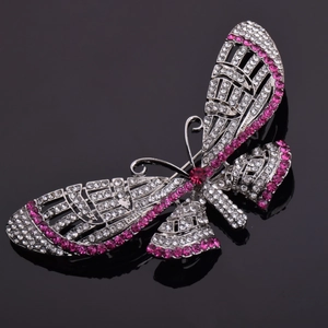 Macro view of crystal butterfly brooch with pink rhinestones on a black reflective surface