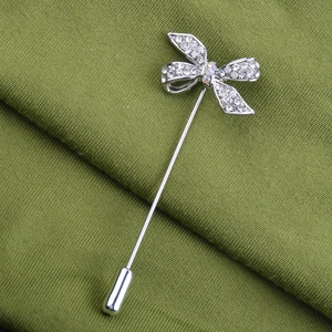 Détail de la broche nœud argentée avec cristaux blancs et diamant AB sur tissu vert
