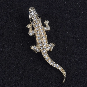 Detailed macro view of gold-plated crocodile brooch with crystal rhinestones and black gem eyes