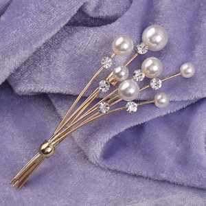 Élégante broche bouquet en or avec perles et strass sur un fond en velours violet de luxe