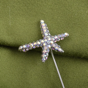 Elegant silver starfish brooch pin with iridescent rhinestones on green knit fabric