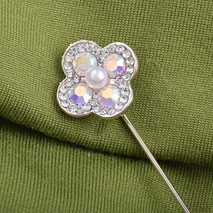 Broche trèfle élégante avec perle et strass colorés sur fond de tissu vert foncé