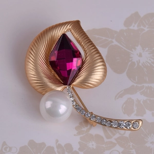 Primer plano del broche de hoja dorada mate con cristal morado, perla y pequeños brillantes