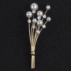 Détail de la broche bouquet dorée ornée de perles blanches et de cristaux étincelants