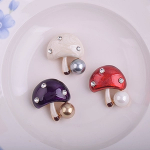 Détail macro de trois broches champignons colorées avec perles et strass sur une assiette