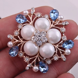 Détail macro d'une broche fleur avec perles, cristaux bleus et cadre en or rose