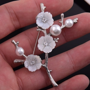 Détail d'une broche fleur en nacre argentée avec centres en cristal et perles