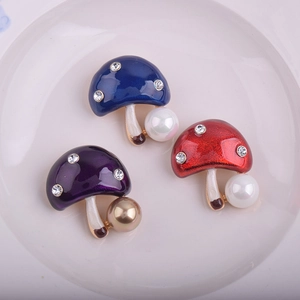 Détail de trois broches champignons colorées avec émail, strass et perles blanches