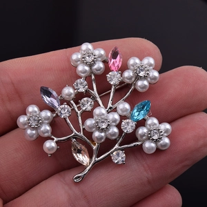Detailed view of luxury tree brooch with colorful crystals and pearls held by hand