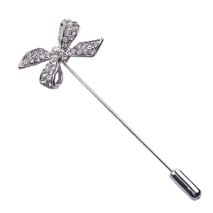 Broche nœud argentée ornée de strass brillants sur fond blanc minimaliste
