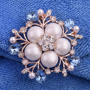 Détail macro de la broche fleur avec cristaux bleus et perles blanches centrales
