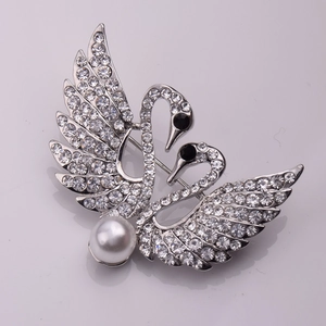 Détail macro de l'élégante broche double cygne avec pavé de cristaux et grosse perle nacre