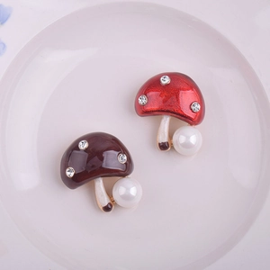 Détail d'une broche champignon avec émail coloré, strass et grandes perles blanches