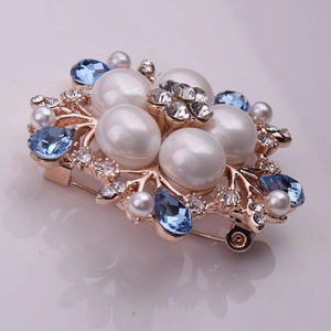 Détail de la base en métal or rose avec perles et cristal bleu sur cette broche fleurie