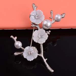 Détail de broche branche argentée avec fleurs en nacre, perles et cristaux étincelants