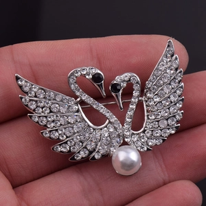 Détail d'une élégante broche cygne avec cristaux étincelants et une grande perle blanche