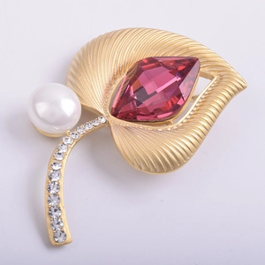 Detalle de broche de hoja de oro mate con gema rosa grande y perla blanca