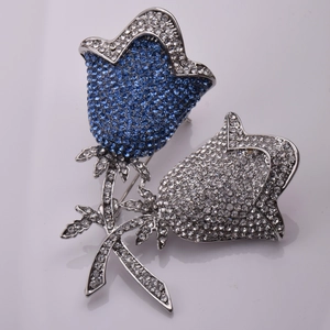 Detail einer eleganten blau-weißen Rosenbrosche mit funkelndem Kristall-Besatz auf Metall