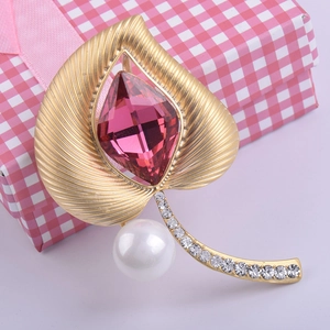 Detalle del broche de hoja en oro mate con cristal rosa facetado y perla blanca