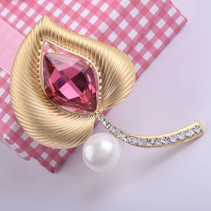Detalle de broche de hoja en oro mate con cristal púrpura y perla blanca elegante
