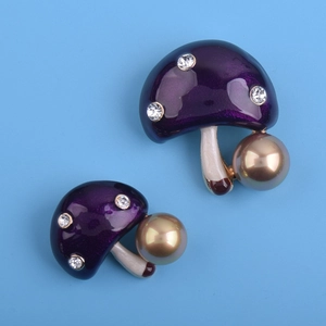 Vue détaillée d'une broche champignon en émail violet avec cristaux et grande perle dorée