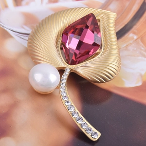 Detalle de broche de hoja dorada vintage con cristal púrpura y perla blanca real
