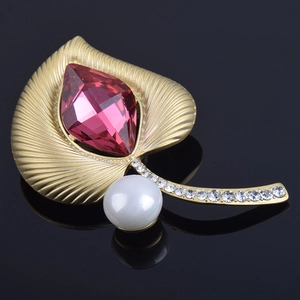 Vista detallada del broche de hoja en oro mate con cristal rosa y perla blanca elegante