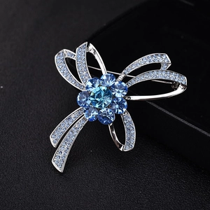 Broche nœud argentée élégante avec cristaux bleu ciel sur un fond noir texturé