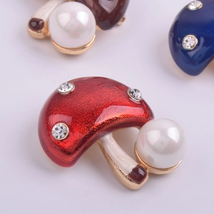 Macro de la broche champignon avec émail rouge, perles blanches et strass étincelants