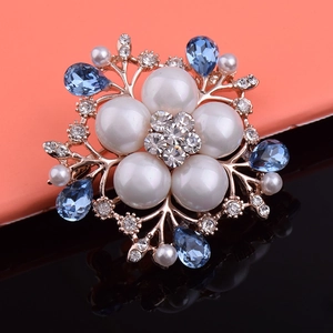 Broche florale élégante avec perles et cristaux bleus sur surface miroir