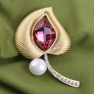 Detalle de broche de hoja de oro estilo étnico con cristal púrpura y perla en tela