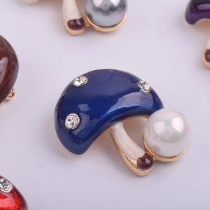 Détail macro d'une broche champignon en émail bleu ornée d'une perle blanche ronde