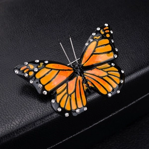 Macro shot of an orange butterfly brooch with sparkling crystals and enamel details