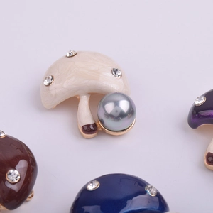 Vue détaillée de broches champignons avec émail marbré, strass et perles