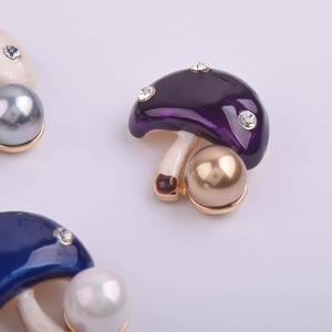 Détail d'une broche champignon en émail violet avec cristaux brillants et perle élégante