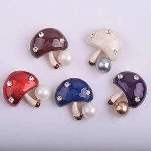Détail de broches en forme de champignon avec perles, émail coloré et strass brillants