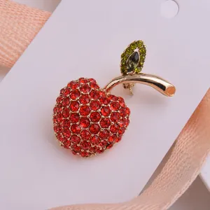 Gros plan sur la broche pomme avec strass rouges et verts sur carte de présentation