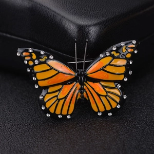 Macro view of butterfly brooch with orange enamel wings and sparkling rhinestones