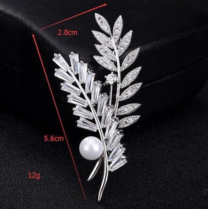 Détail macro d'une broche feuille avec micro-pavage de zircons et une grande perle blanche