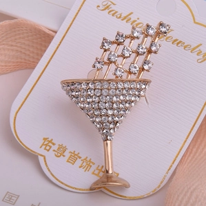 Détail d'une broche en verre à cocktail avec strass étincelants sur fond de tissu rose