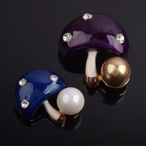 Détail de broches champignon en émail avec perles et cristaux sur surface noire miroir